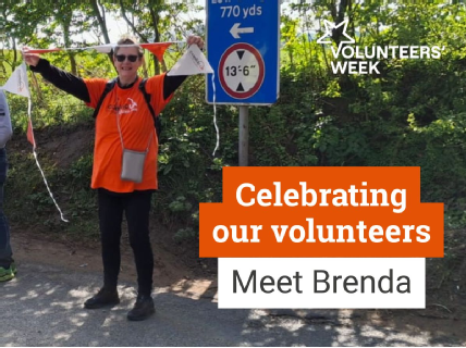 Coeliac UK volunteer Brenda smiling outdoors, wearing an orange Coeliac UK T-shirt, with orange bunting in the background.